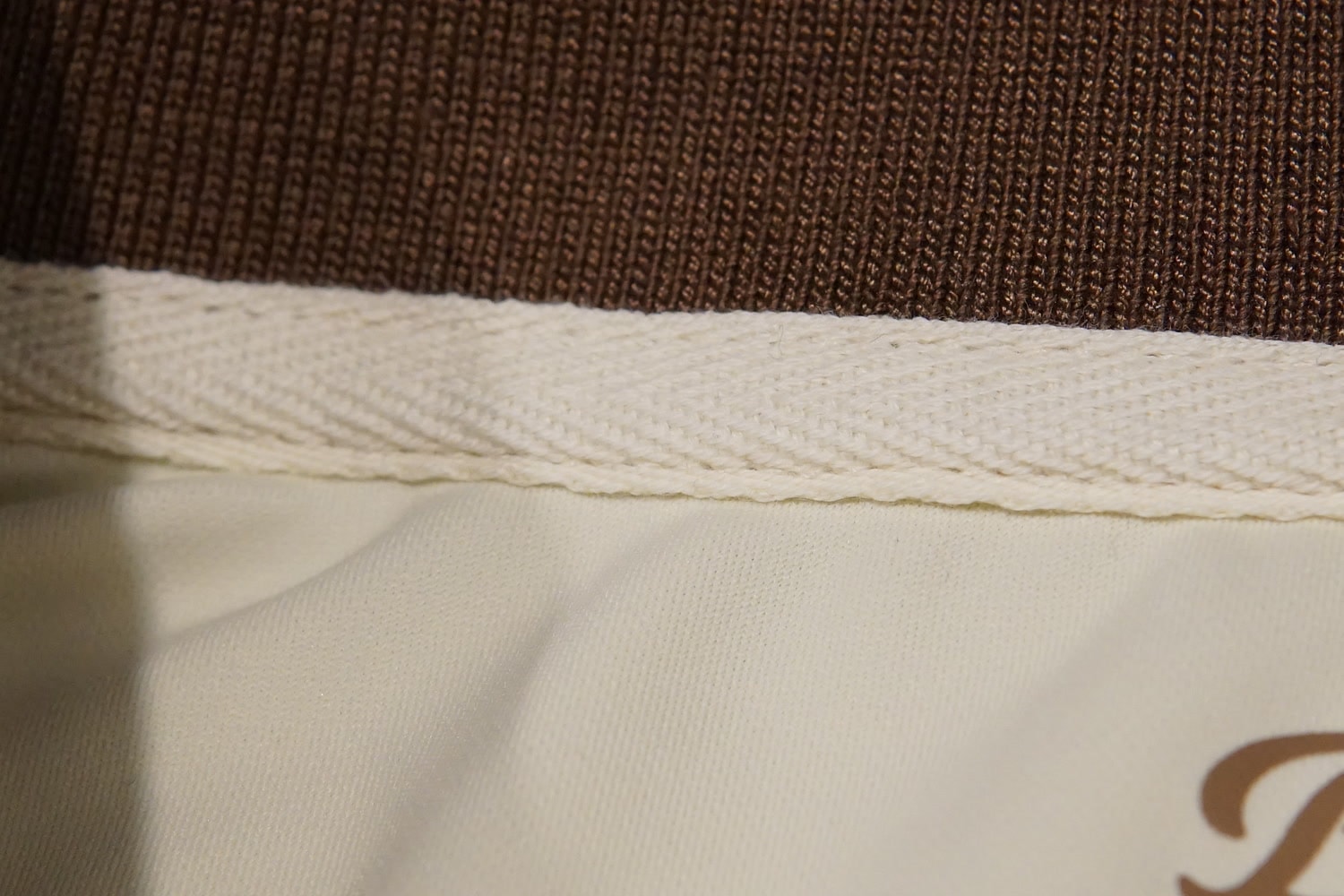Cream herringbone tape inlay beneath the brown knit collar