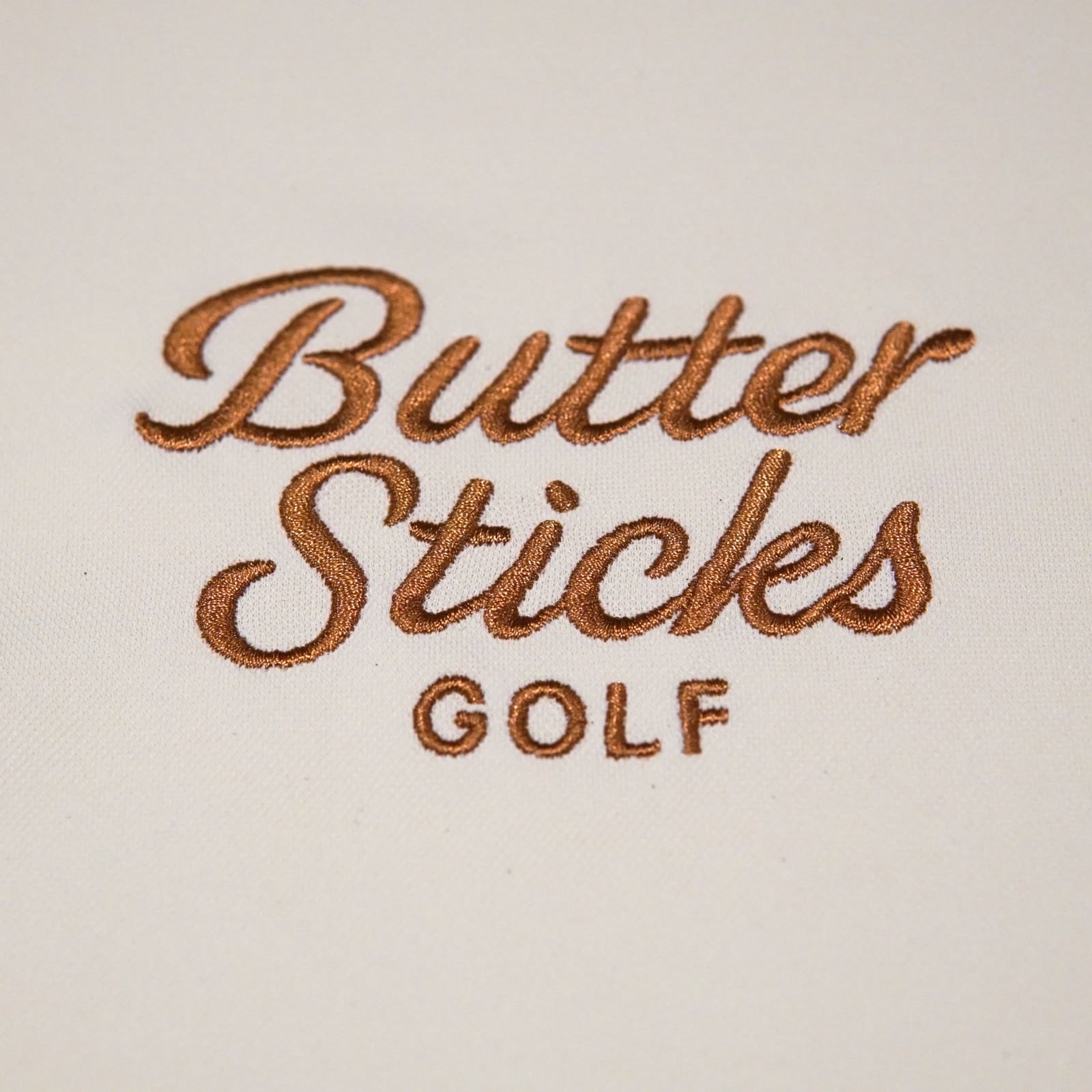 Close-up of the embroidered Butter Sticks Golf script in brown thread